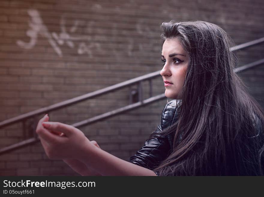 Serious girl sits on street ladder