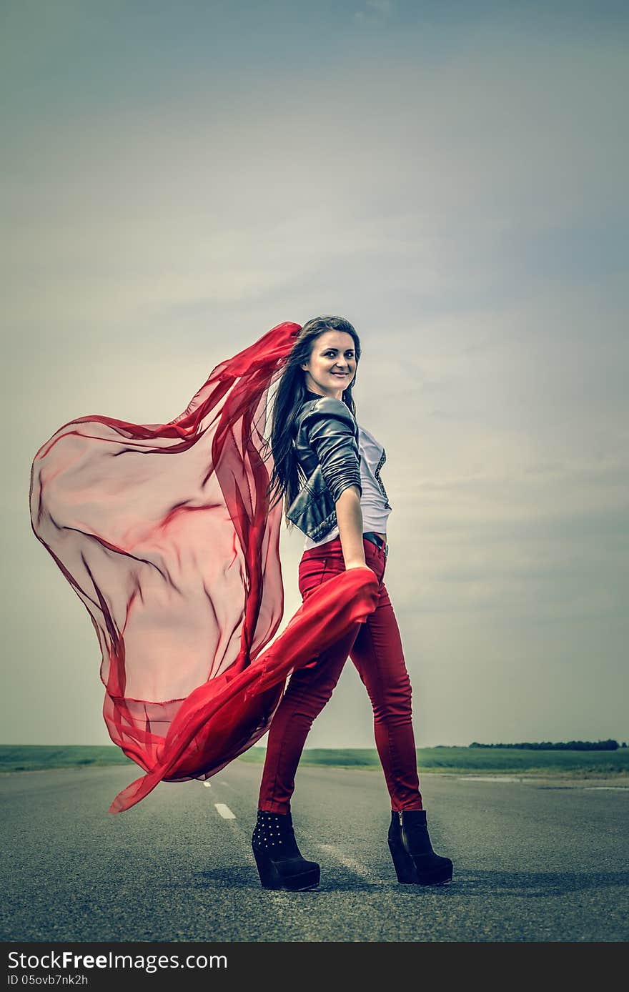 Beautiful girl on the road with veil opening wide from wind