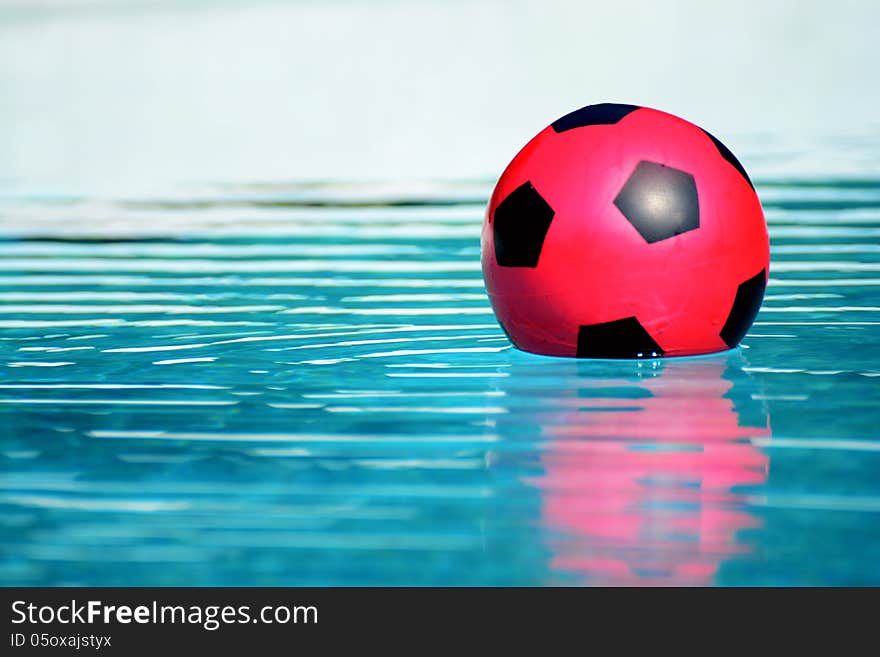 A red ball floating in a swimming pool closeup. A red ball floating in a swimming pool closeup