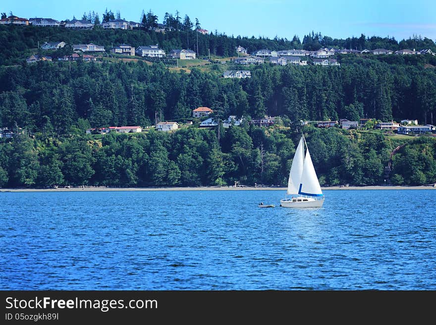 A sailboat under blue skies, view of an island community behind. Copy space. A sailboat under blue skies, view of an island community behind. Copy space.