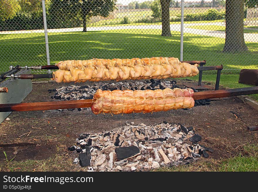 Fresh chicken and pork loin being roasted to a golden brown on a spit, over hot charcoal. Photo taken July 4, 2013. Fresh chicken and pork loin being roasted to a golden brown on a spit, over hot charcoal. Photo taken July 4, 2013.