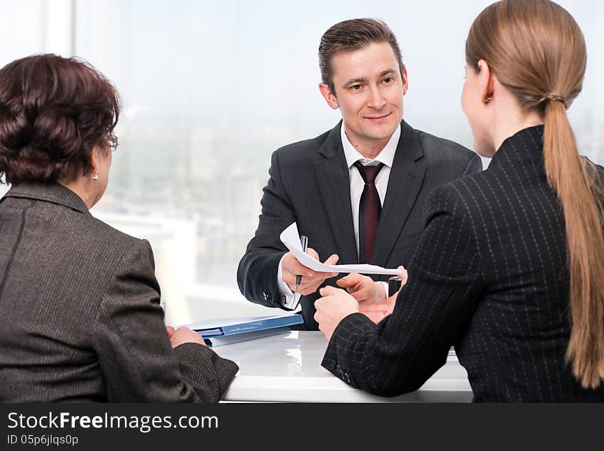 Agent (or notary public) signing documents with with senior women and her daughter. Agent (or notary public) signing documents with with senior women and her daughter