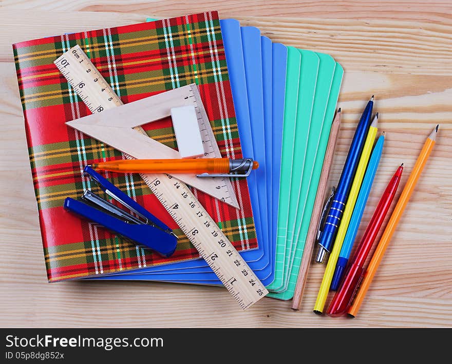 Notebooks,ruler,triangle, pen and pensil on the table