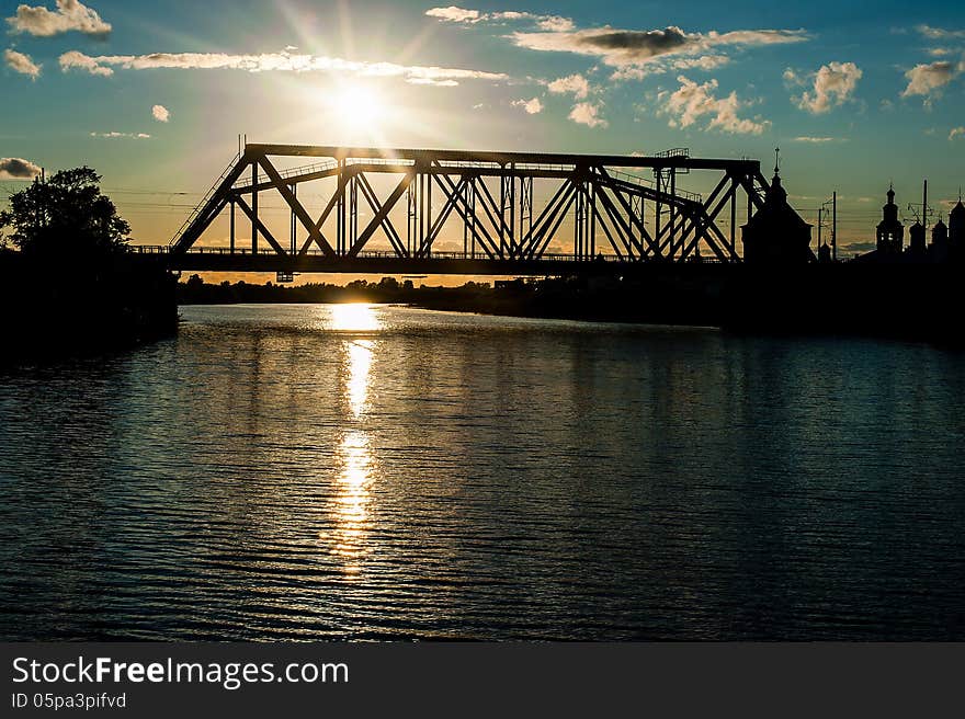 Silhouette of the railway bridge through the river at sunset or sunrise