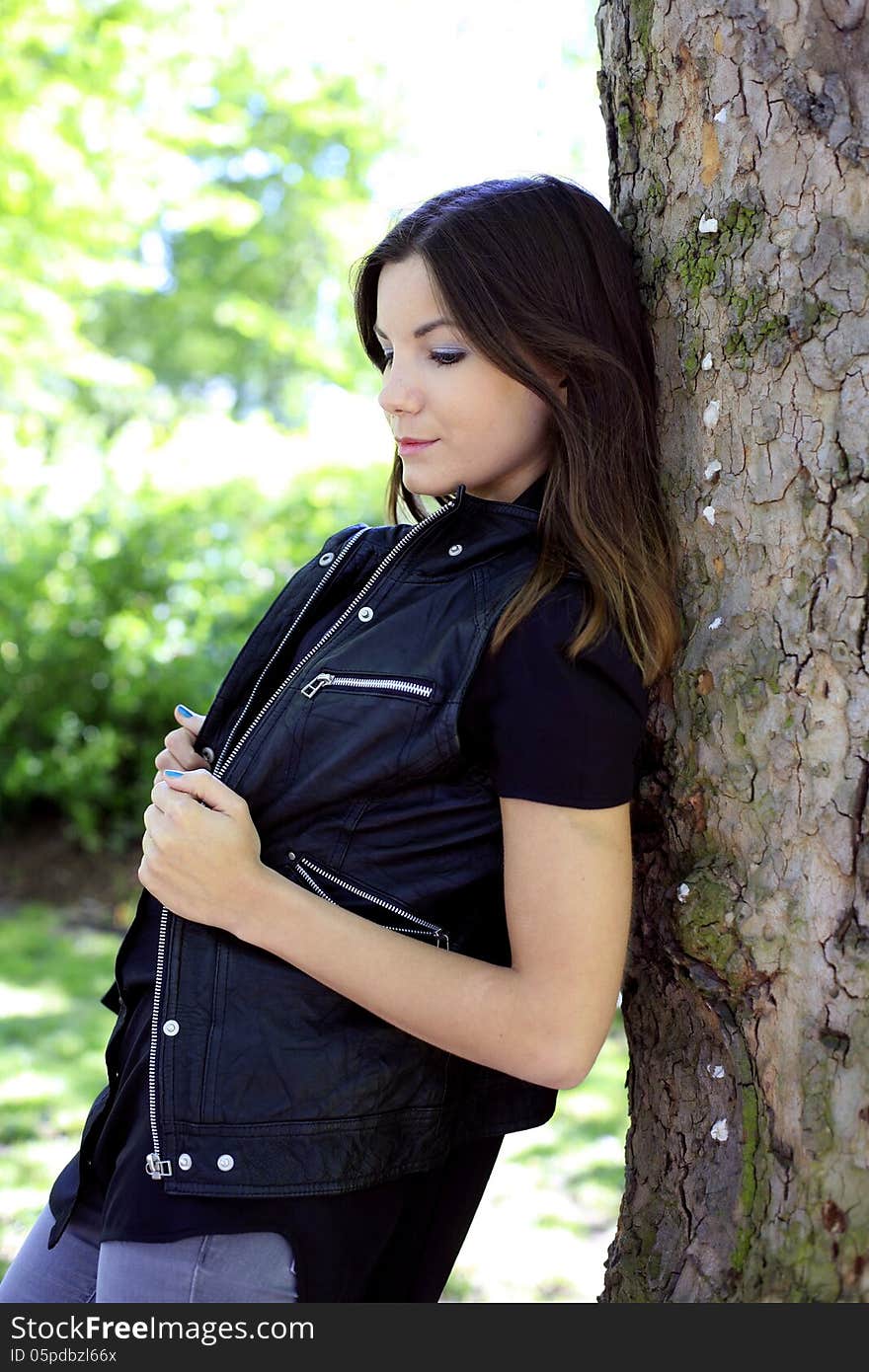 Beautiful girl standing near the tree, vertical, profile. Beautiful girl standing near the tree, vertical, profile