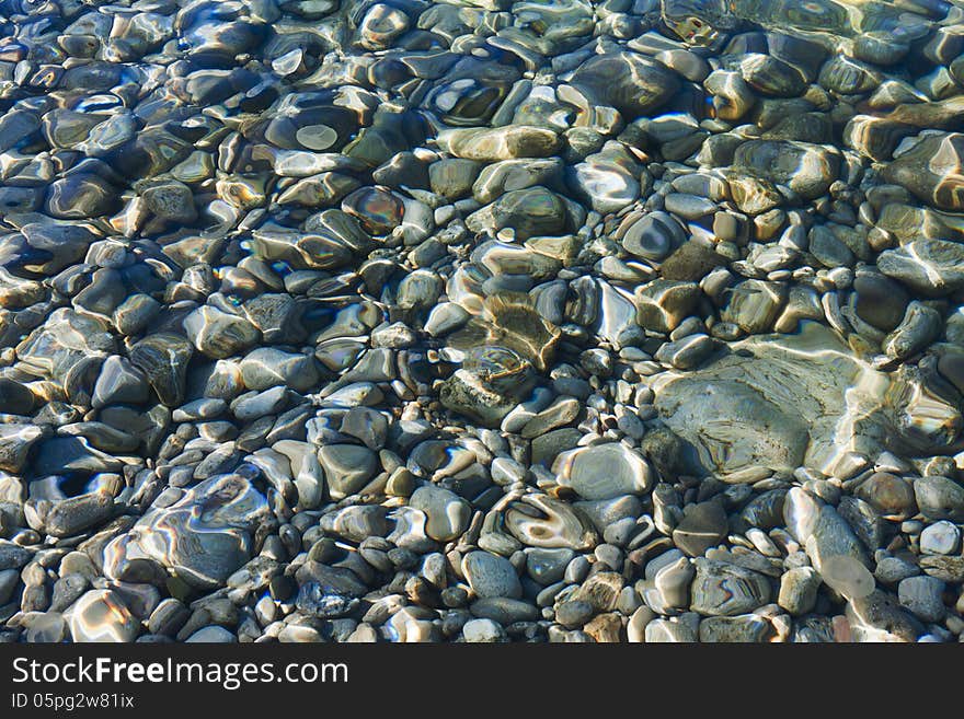 Pebbles under the clear sea water, natural background