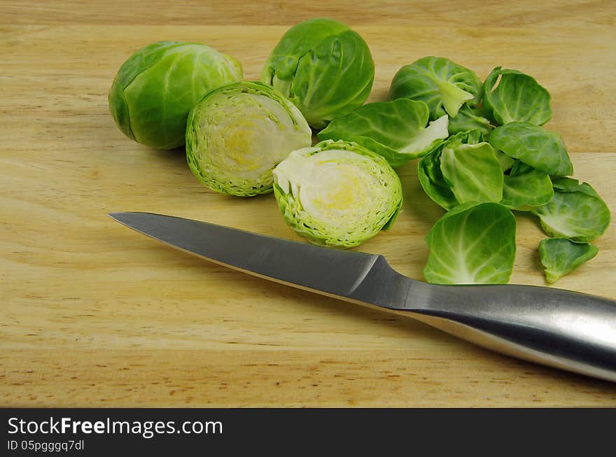 Brussel sprouts cut and peeled with silver knife on wooden background. Brussel sprouts cut and peeled with silver knife on wooden background