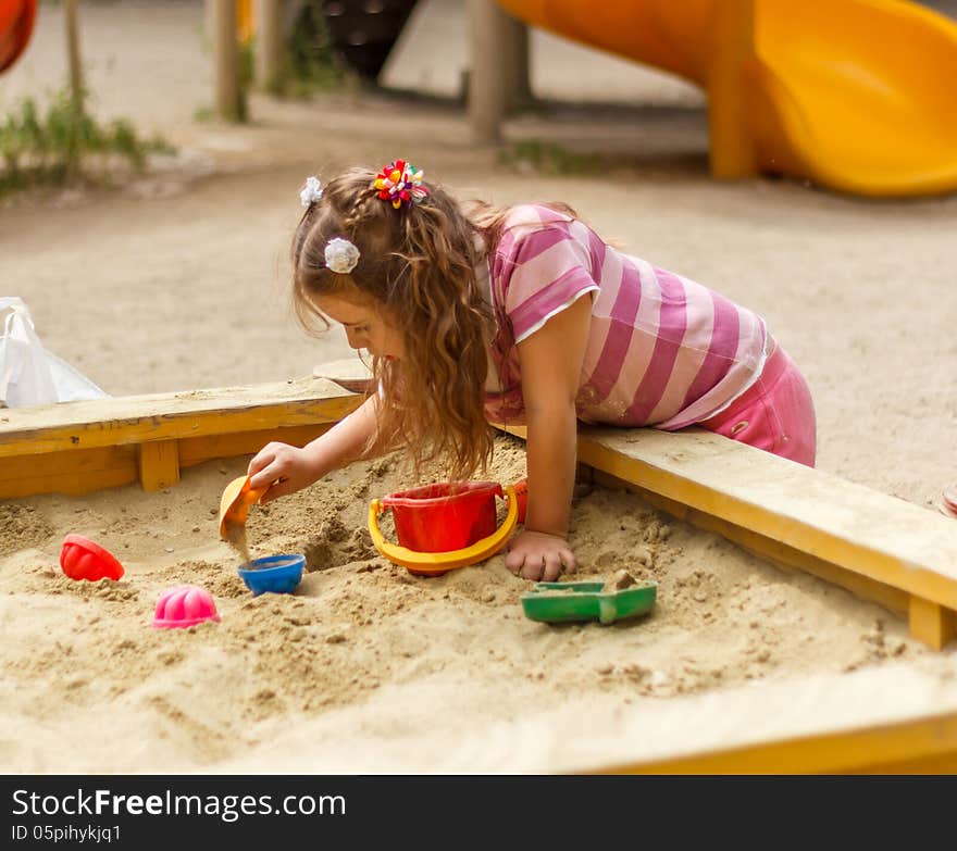 Little girl playing in the sandbox. Little girl playing in the sandbox