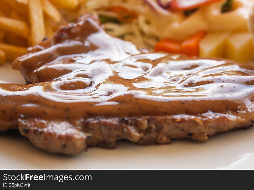 Pork chop steak with black pepper gravy salad and french fries