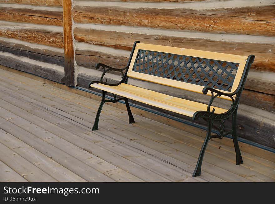 Empty Bench in front of Log Cabin setting on wooden walkway. Empty Bench in front of Log Cabin setting on wooden walkway.