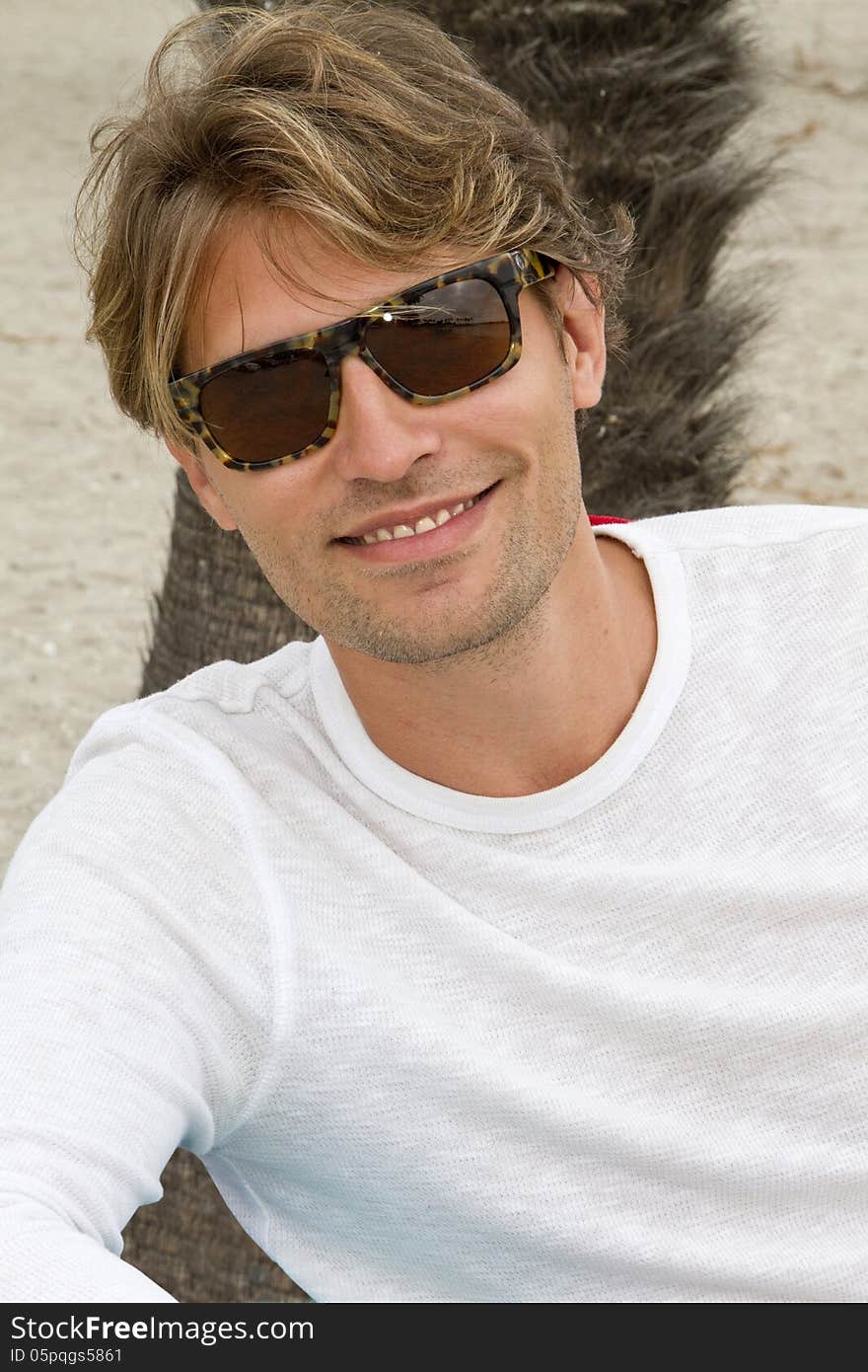 Young male wearing sunglasses on vacation at the beach. Young male wearing sunglasses on vacation at the beach