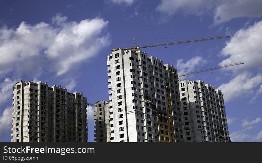 Buildings under construction against blue sky with white clouds.