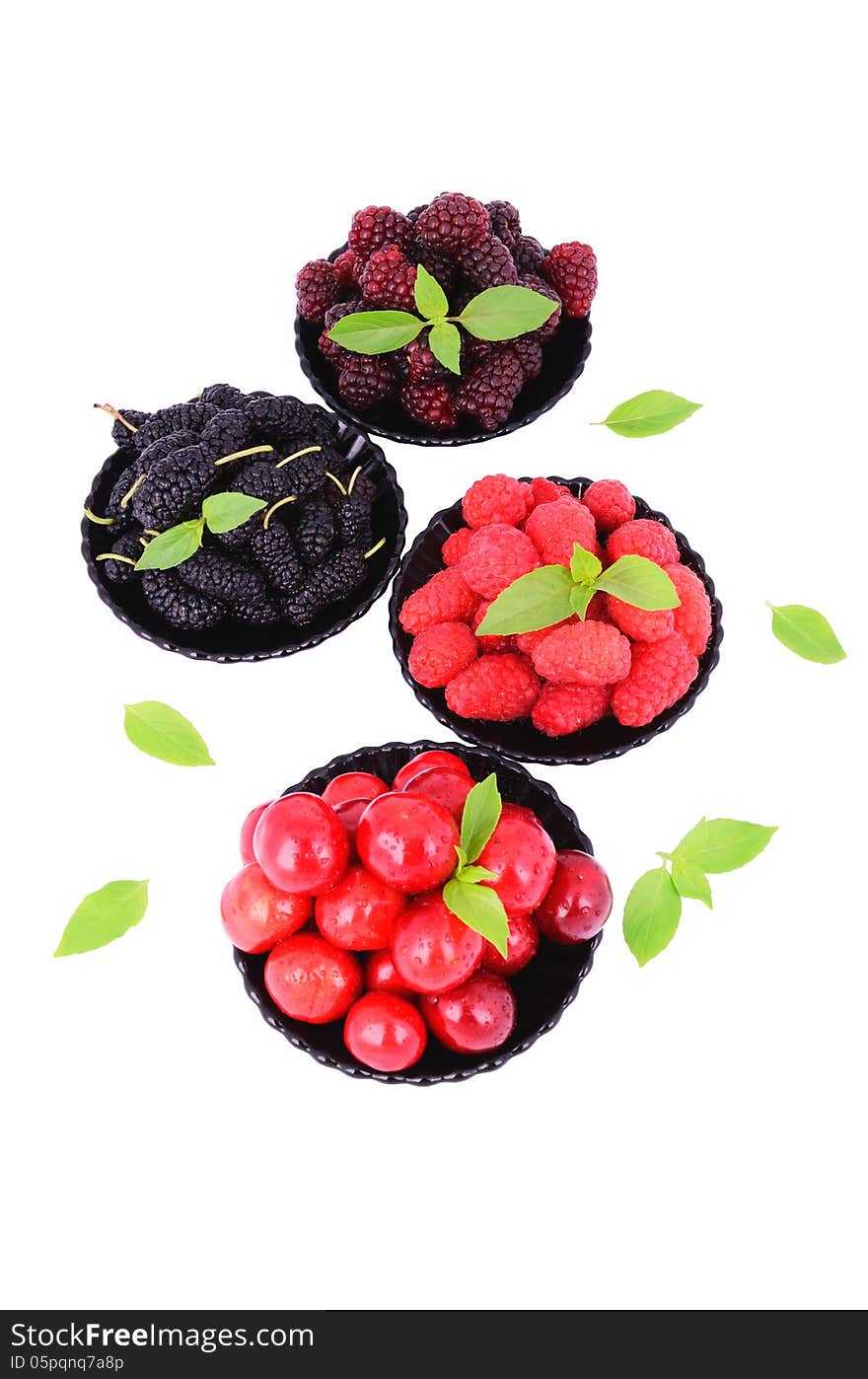 Mulberry; cherry; raspberry; blackberry in a plates close-up isolated on white; decorated with green leaves. Mulberry; cherry; raspberry; blackberry in a plates close-up isolated on white; decorated with green leaves