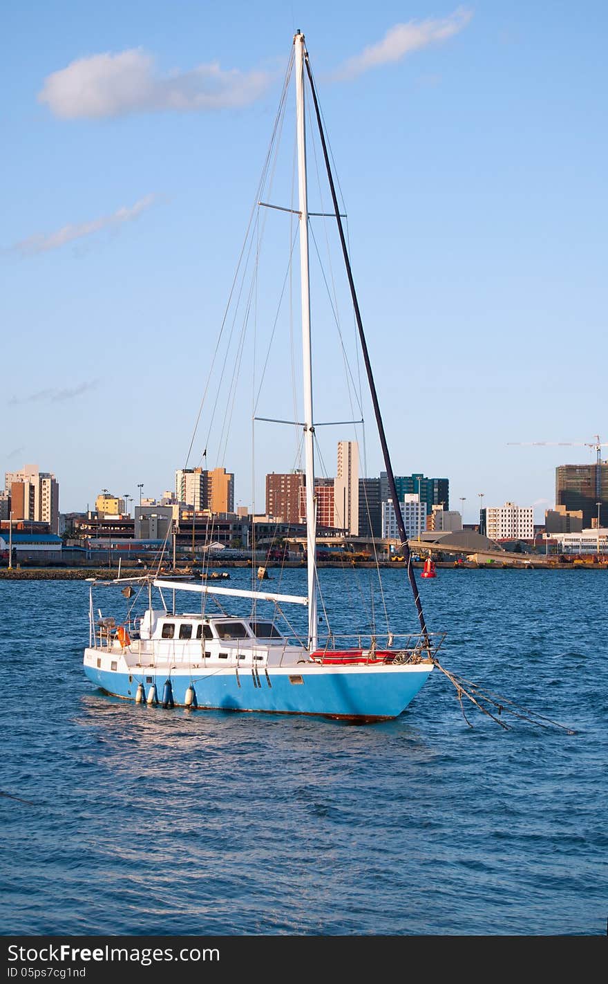 A yacht lying at anchor in Durban harbour, KwaZulu-Natal, South Africa, with the city skyline in the background. A yacht lying at anchor in Durban harbour, KwaZulu-Natal, South Africa, with the city skyline in the background