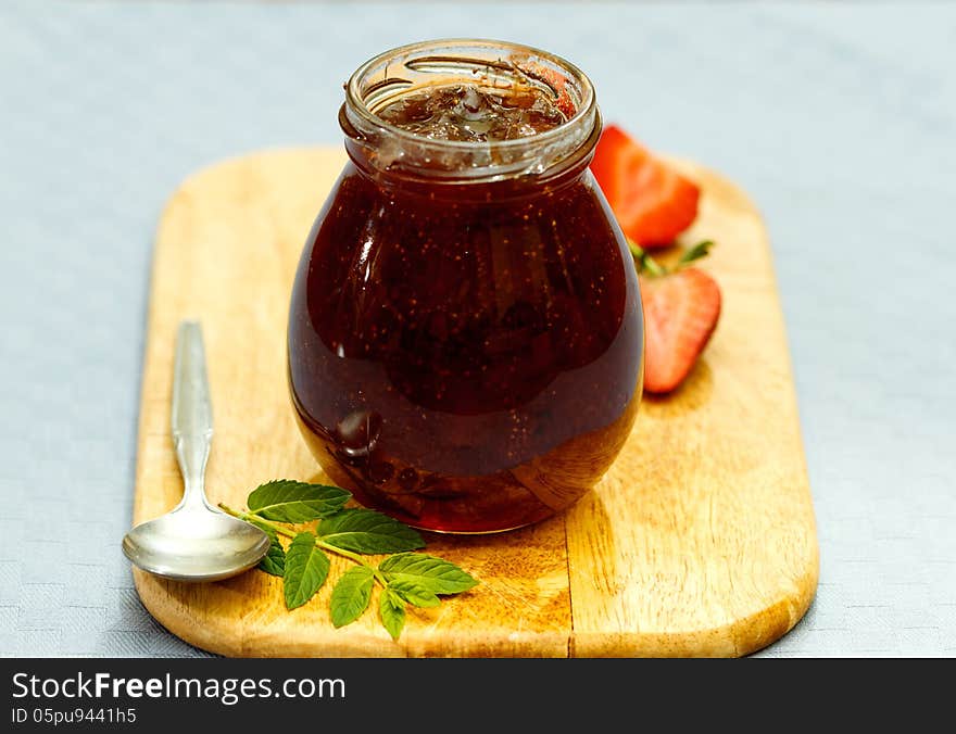 Strawberry jam and fresh fruits on wooden cutting board