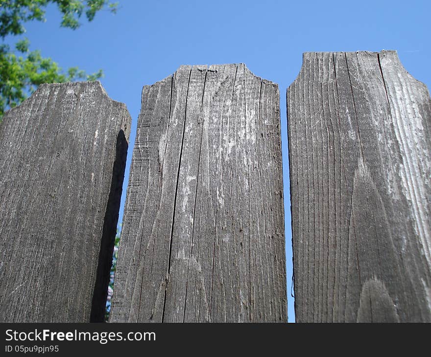 Top of old wooden fence on blue sky. Top of old wooden fence on blue sky