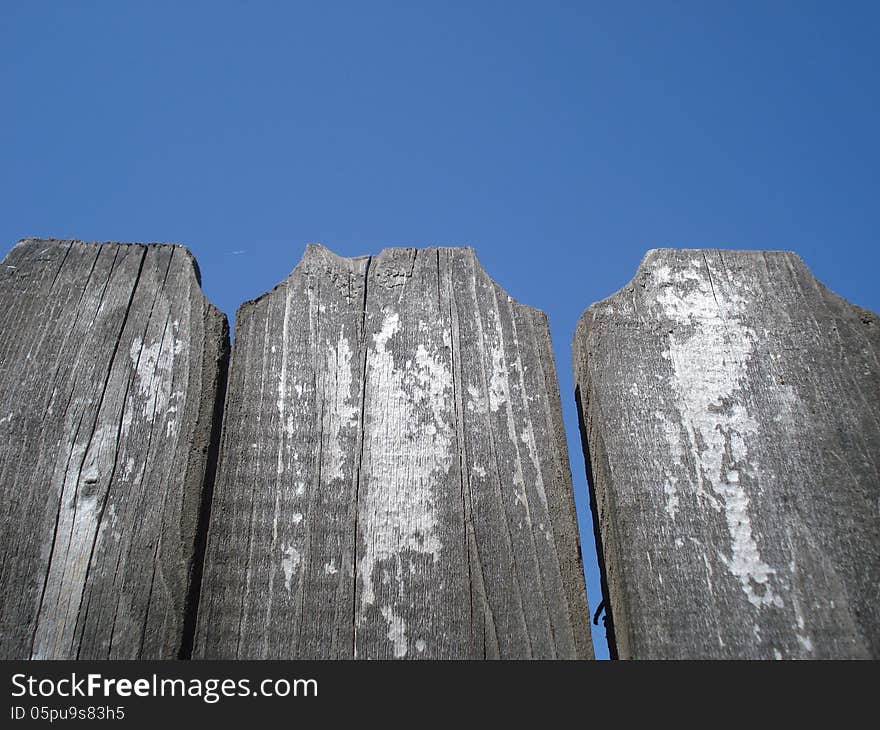 Top of old wooden fence on blue sky. Top of old wooden fence on blue sky