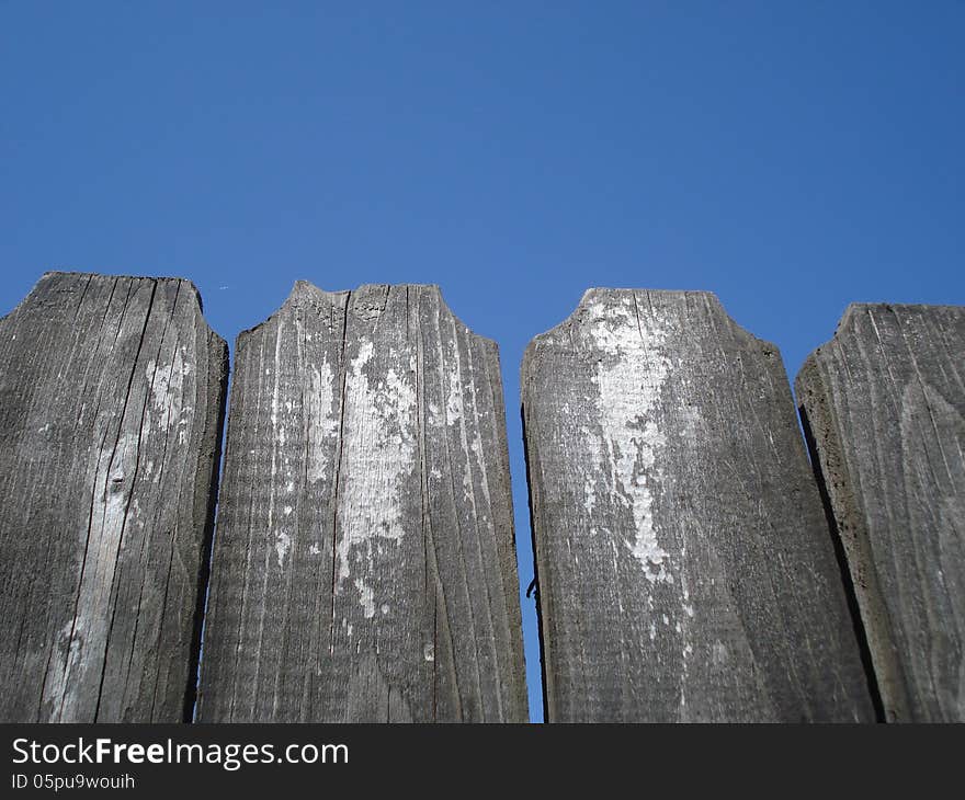 Top of old wooden fence on blue sky. Top of old wooden fence on blue sky