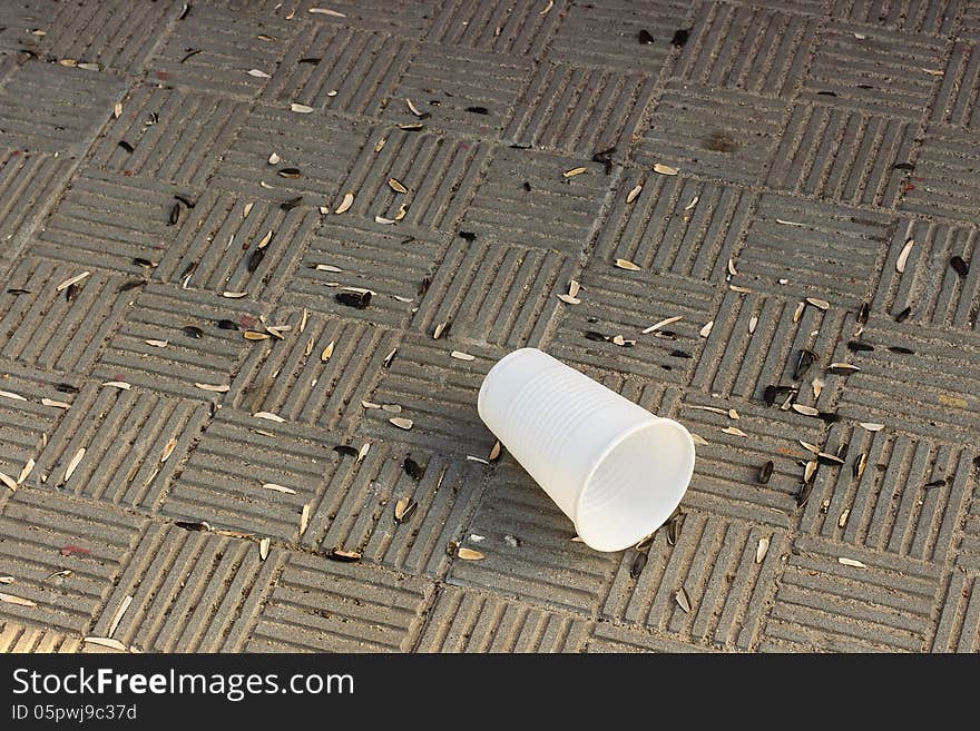 Husks sunflower seeds and a cup on a stone tile