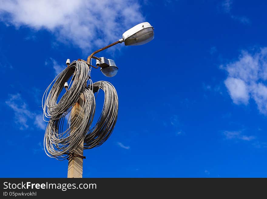 A coils of metal wire hangigns on a lamppost over blue sky. A coils of metal wire hangigns on a lamppost over blue sky