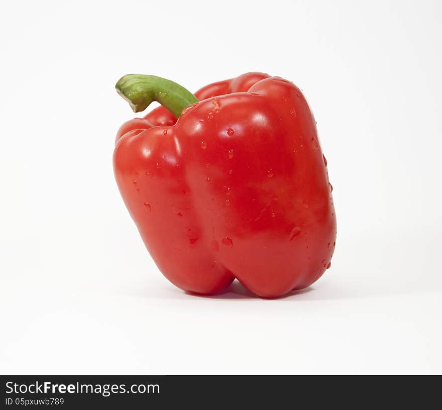 Red pepper with water droplets against a white background