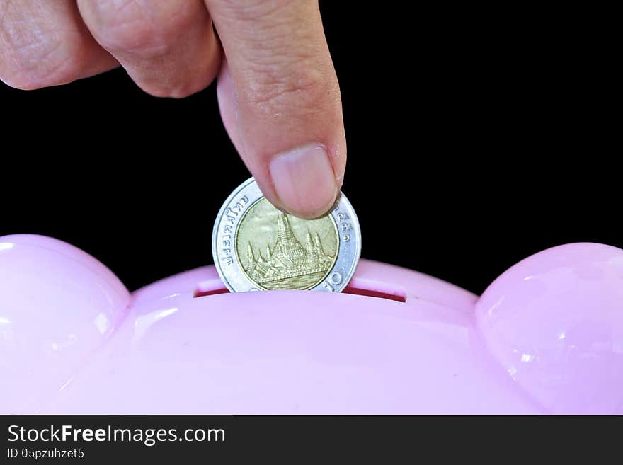 Hand inserting coin into piggy bank. Hand inserting coin into piggy bank