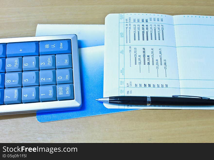 Accounting Calculator, pen and Bank account on table