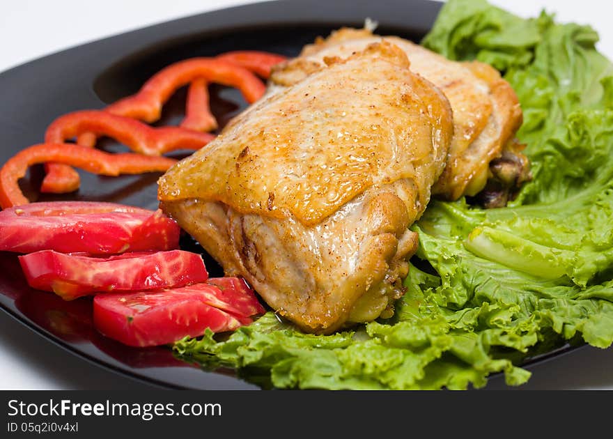 Tasty dish of roast chicken with vegetables on a black plate. Tasty dish of roast chicken with vegetables on a black plate