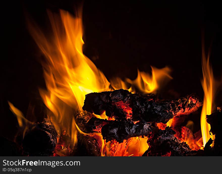 Live coals with fire flames on black background