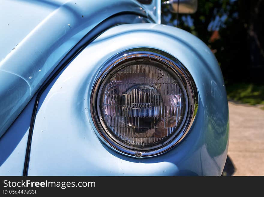 Close-up of the headlight of a vintage light blue Volkswagen beetle