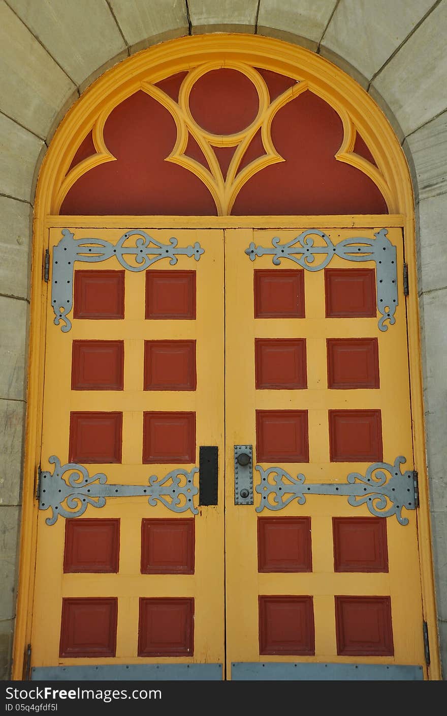 Old red and yellow ornate church door in wooden wall