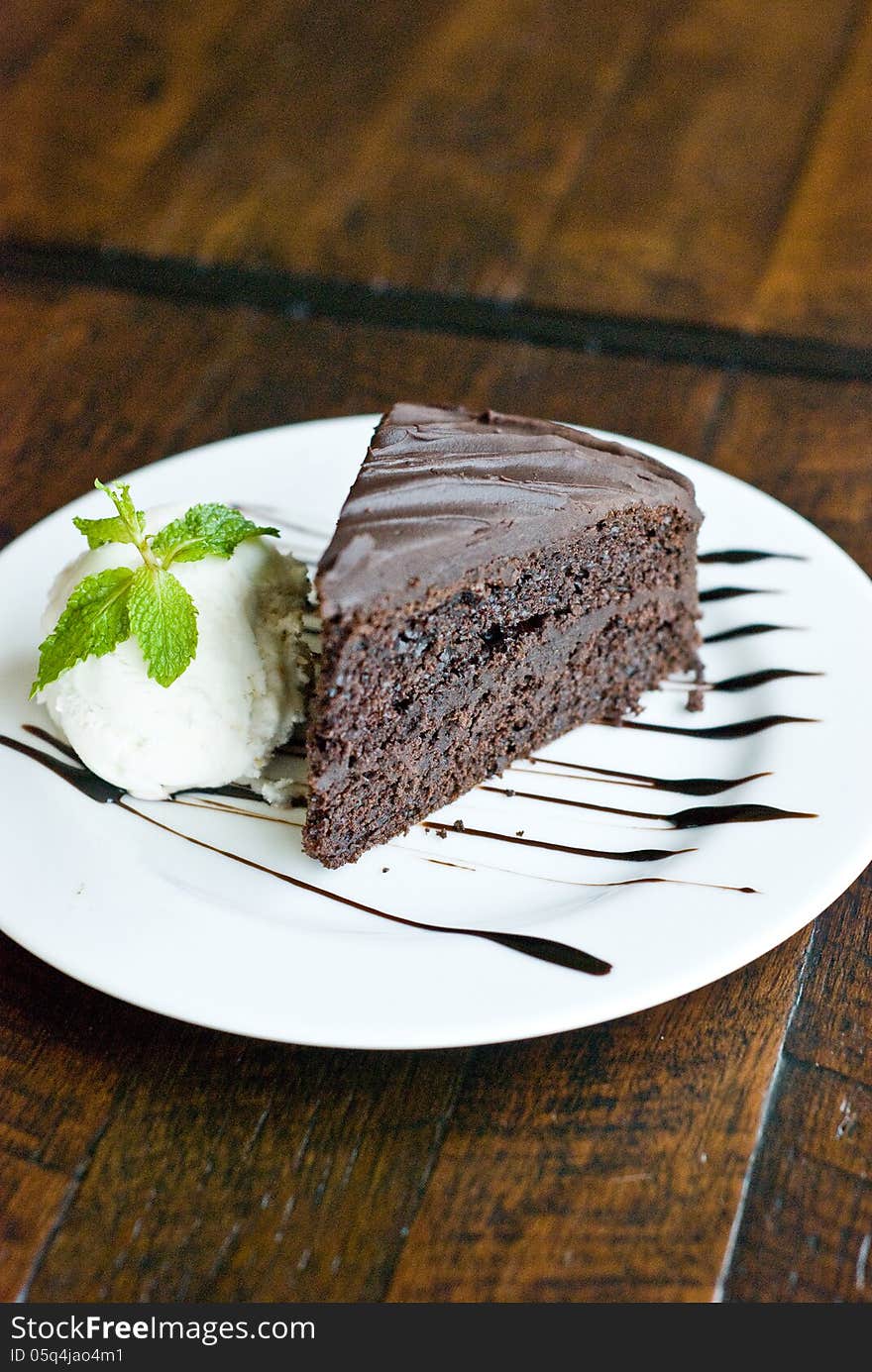 Portion of chocolate cake with vanila ice-creme on white plate topping with chocolate sauce