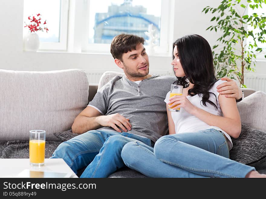 Couple Sitting On Couch And Drinking Orange Juice