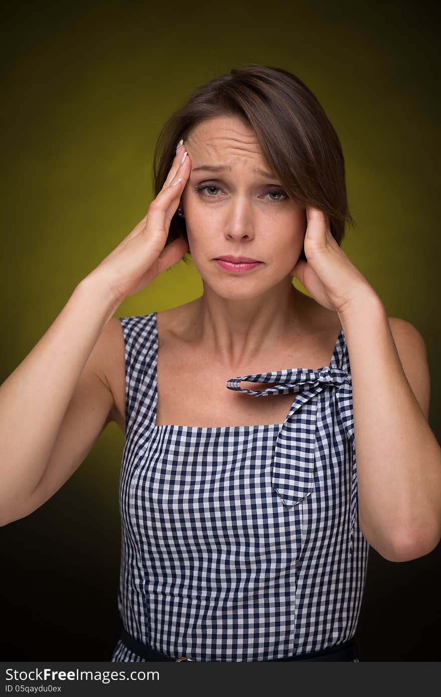 Beautiful woman with headache on golden-dark background