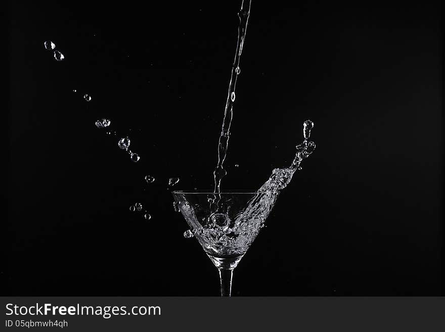 Pouring water into glass with black background. Pouring water into glass with black background