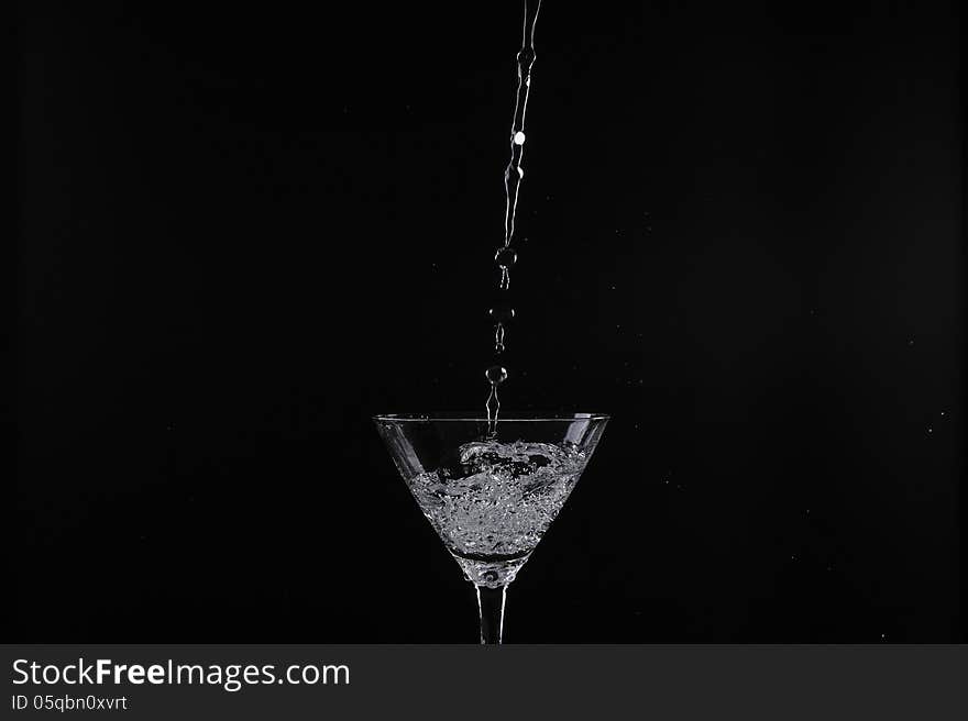 Pouring water into glass with black background. Pouring water into glass with black background