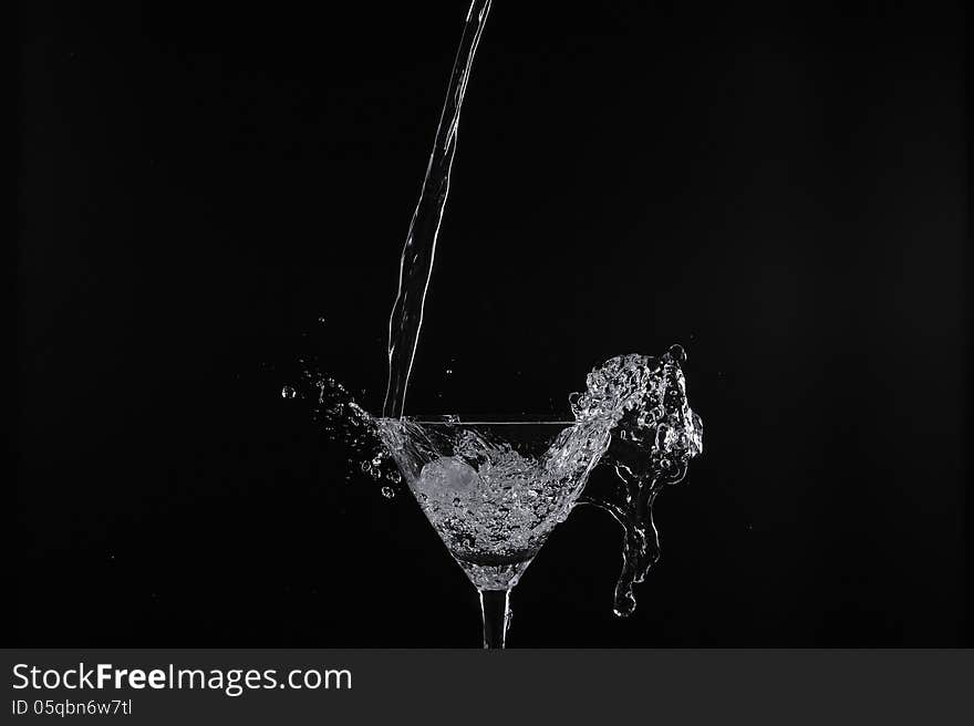 Pouring water into glass with black background. Pouring water into glass with black background