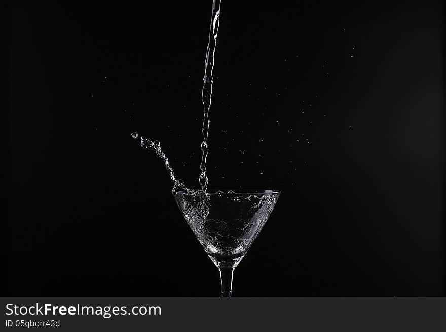 Pouring water into glass with black background. Pouring water into glass with black background