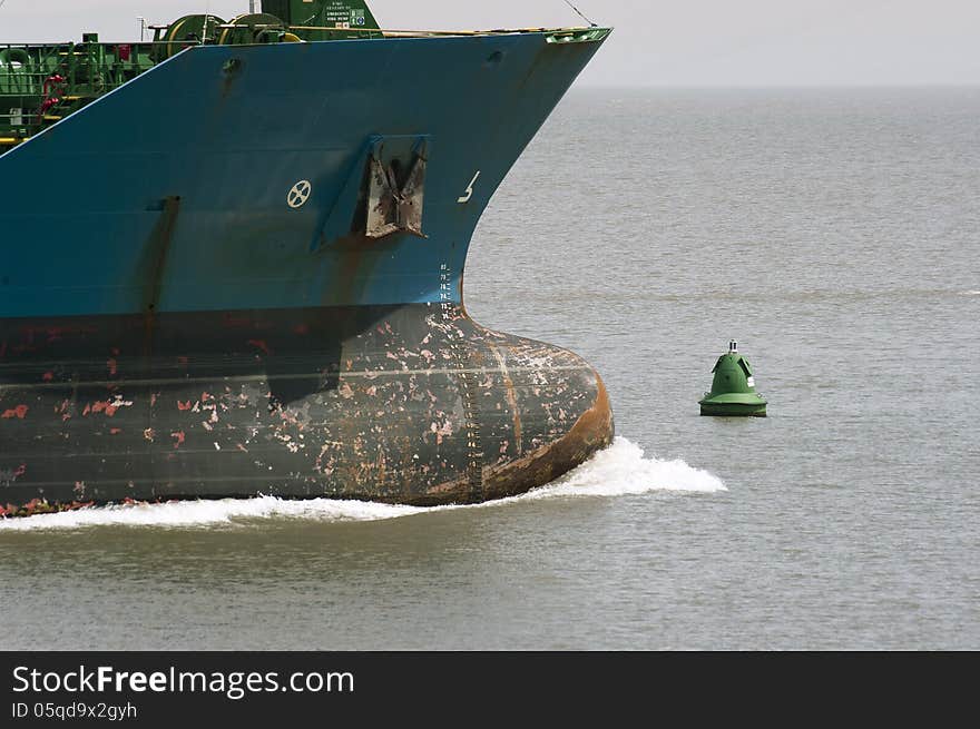 Bulbous bow of unladen cargo vessel under way with green navigation buoy. Bulbous bow of unladen cargo vessel under way with green navigation buoy.