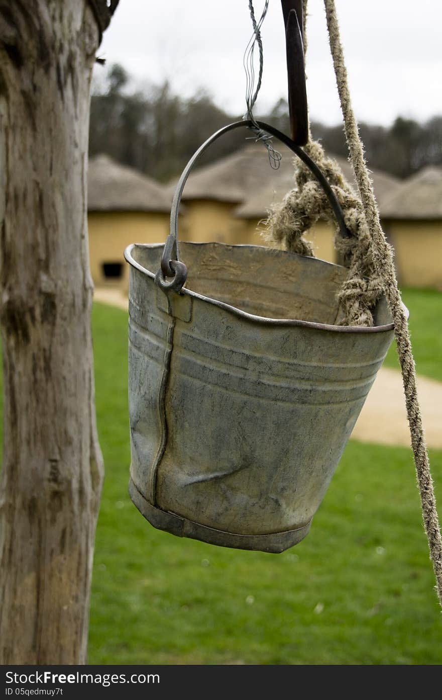 Bucket of a water well with African cabins in the background