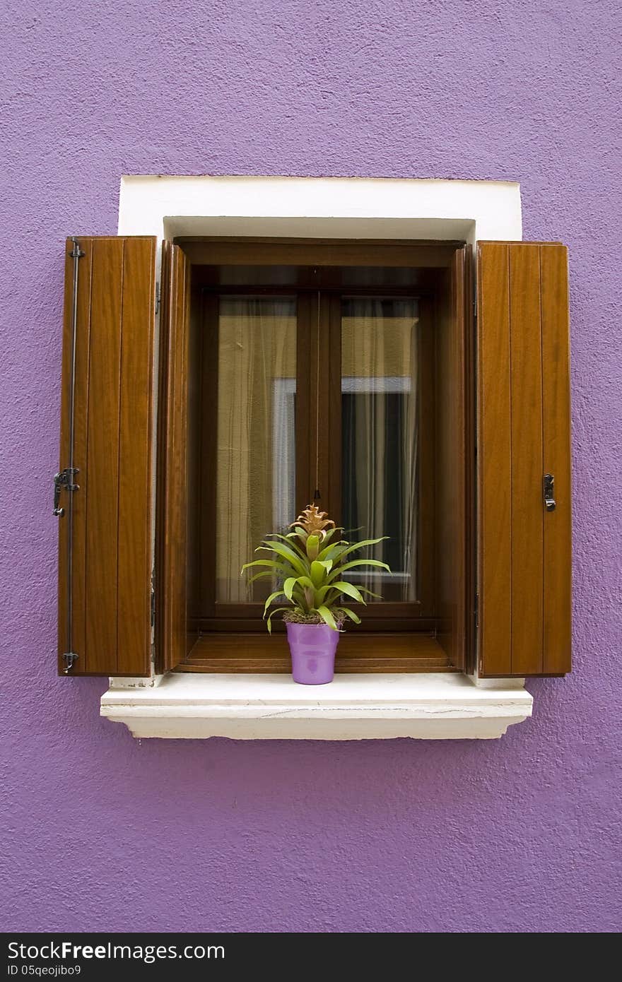 Lilac house with a window with wooden shutters and a plant in pot in Burano near Venice. Lilac house with a window with wooden shutters and a plant in pot in Burano near Venice