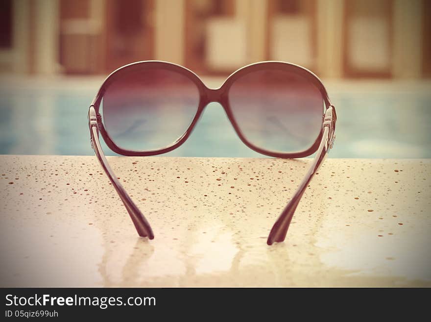 Fashionable women's sunglasses lying near the water. Fashionable women's sunglasses lying near the water