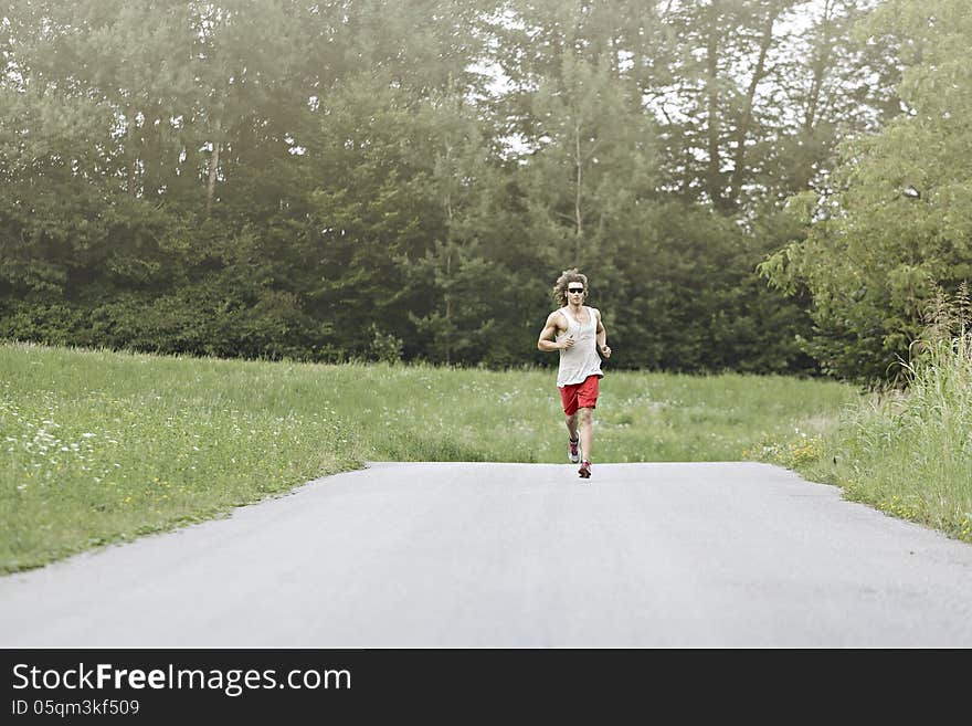 Long hair athlete runs in the middle of road. Long hair athlete runs in the middle of road