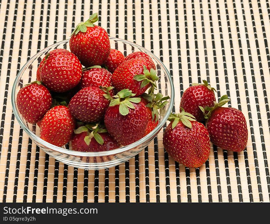 Strawberry in a glass vase on a wattled mat