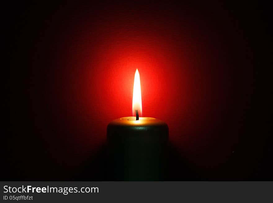 Burning gold candle on the red background. Burning gold candle on the red background