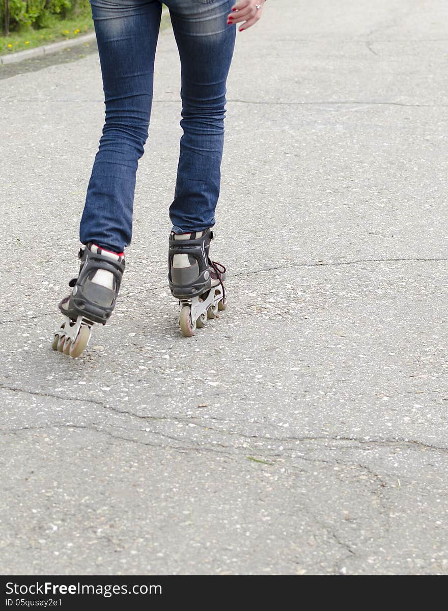 Girl rides on roller skates on asphalt. Legs in rollers