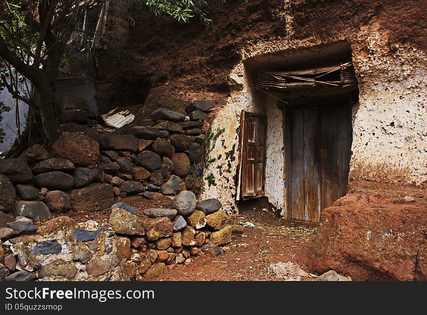 Pathway leading to a closed old wooden door and window in a dilapidated broken down rustic shack