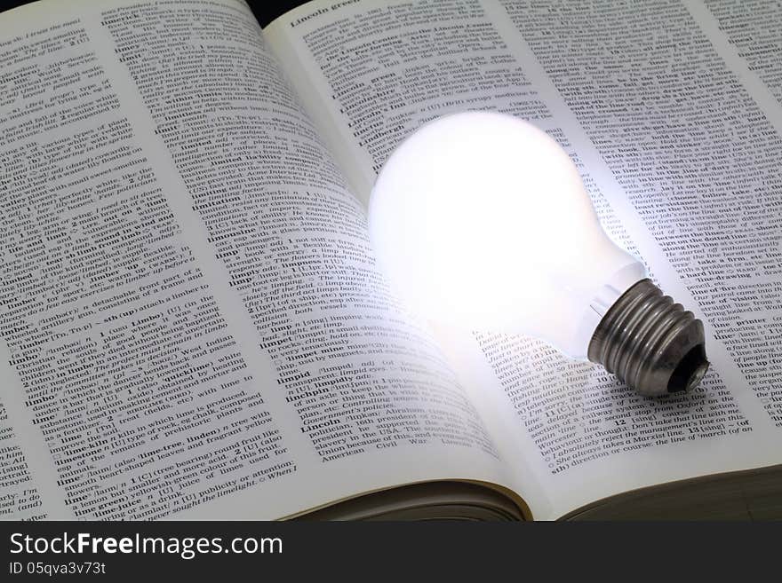 Illuminated light bulb glowing on a book