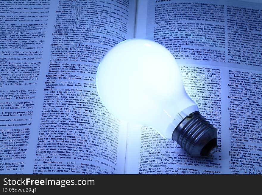 Illuminated light bulb glowing on a book