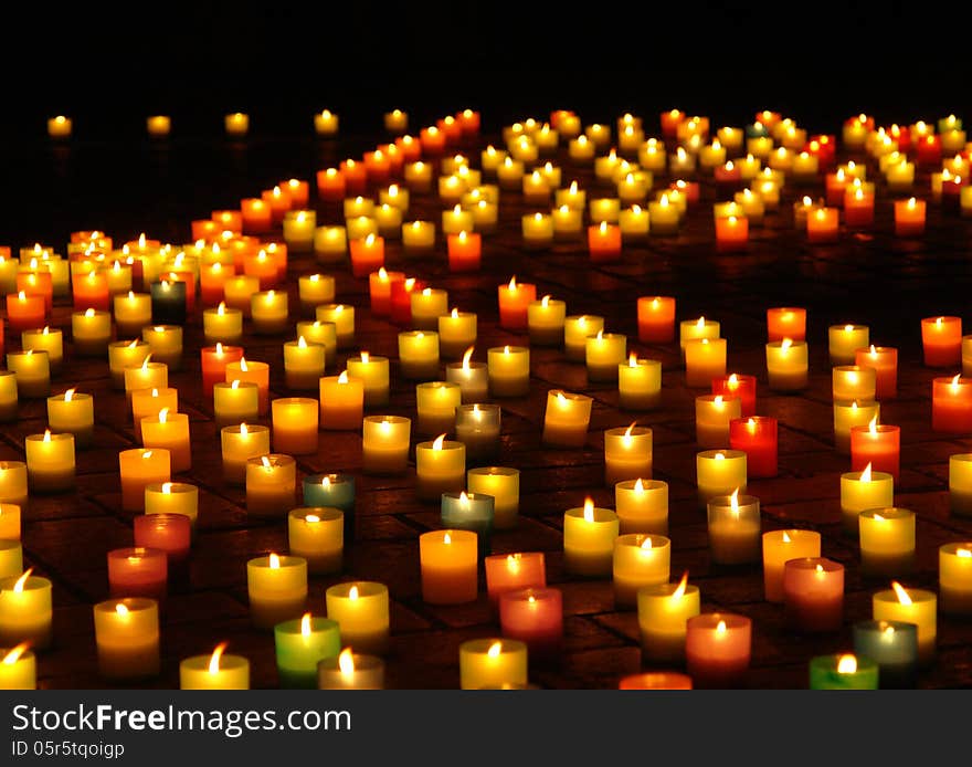 Multicolored lighted candles on the sidewalk at night with local focus. Multicolored lighted candles on the sidewalk at night with local focus